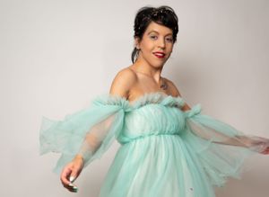 Figure twirls in a flowing mint green tulle dress against studio backdrop.