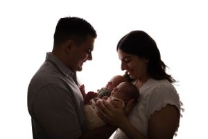 Silhouetted family portrait with parents lovingly cradling their newborn.