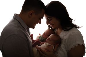 Intimate silhouette portrait of parents sharing tender moment with their newborn baby.
