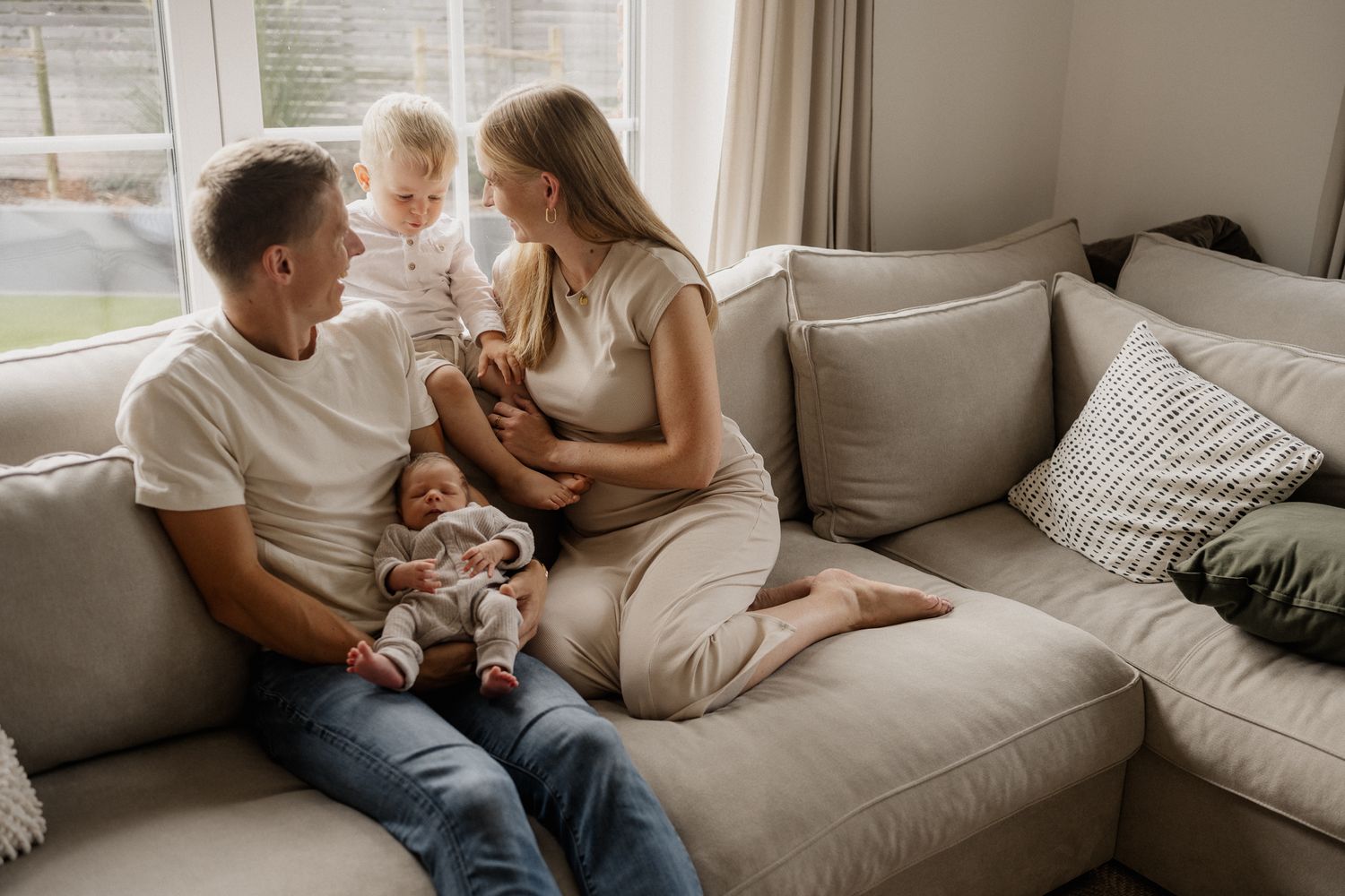 A family shares a tender moment together while relaxing on a comfortable gray couch in their living room.