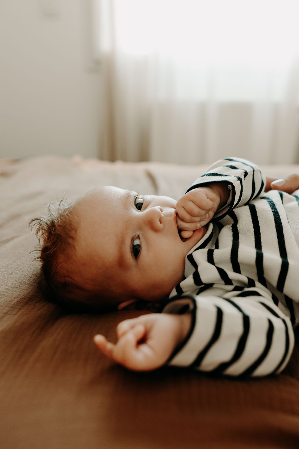 A series of candid photos showing a person lying down in a black and white striped shirt against a light background.