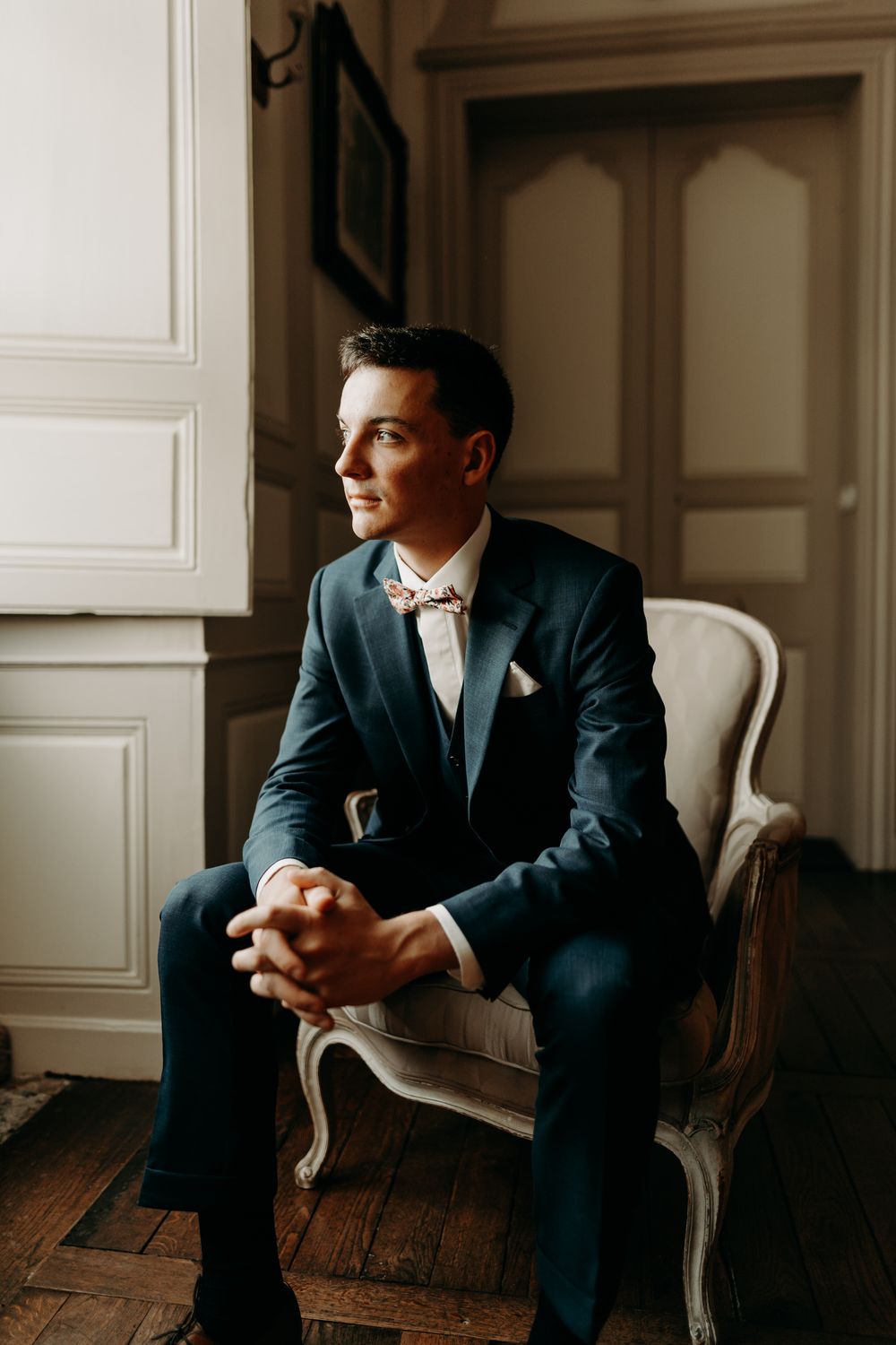 Formal portrait in a classic room with antique furniture and wooden floors.