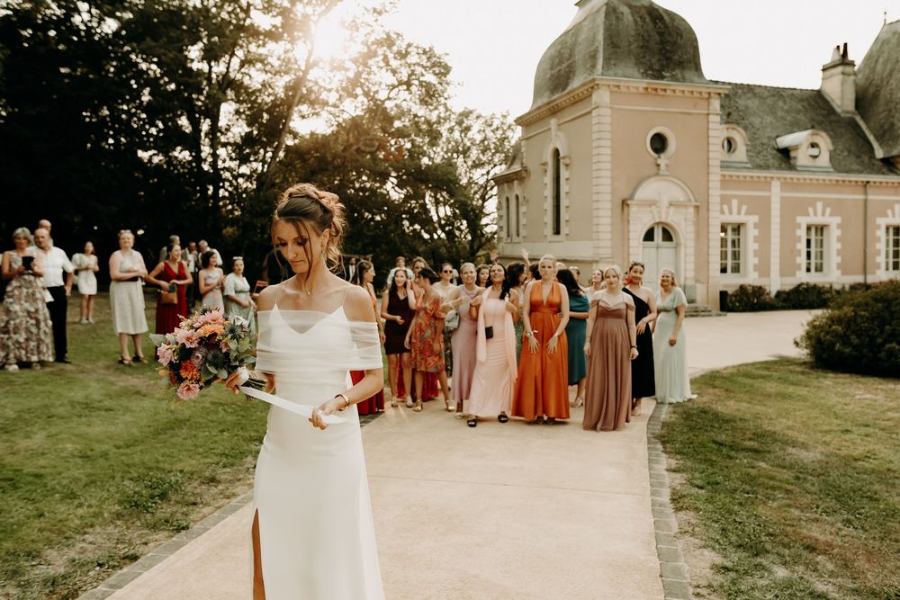 Wedding party gathers outside elegant white chapel building during golden hour celebration.