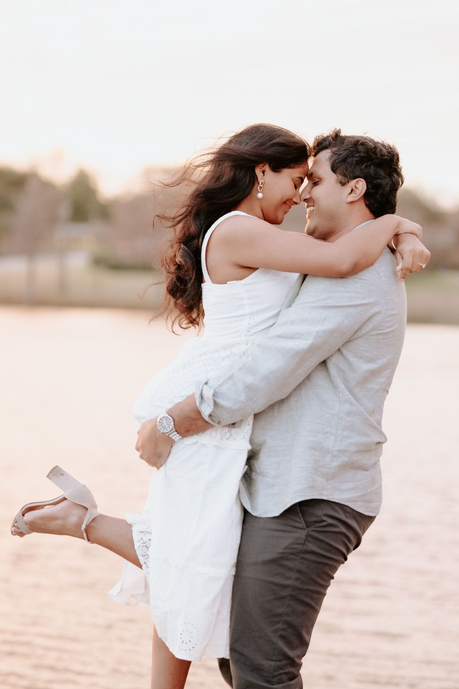 A romantic couple embraces and spins on a beach at sunset in a dreamy photoshoot sequence.
