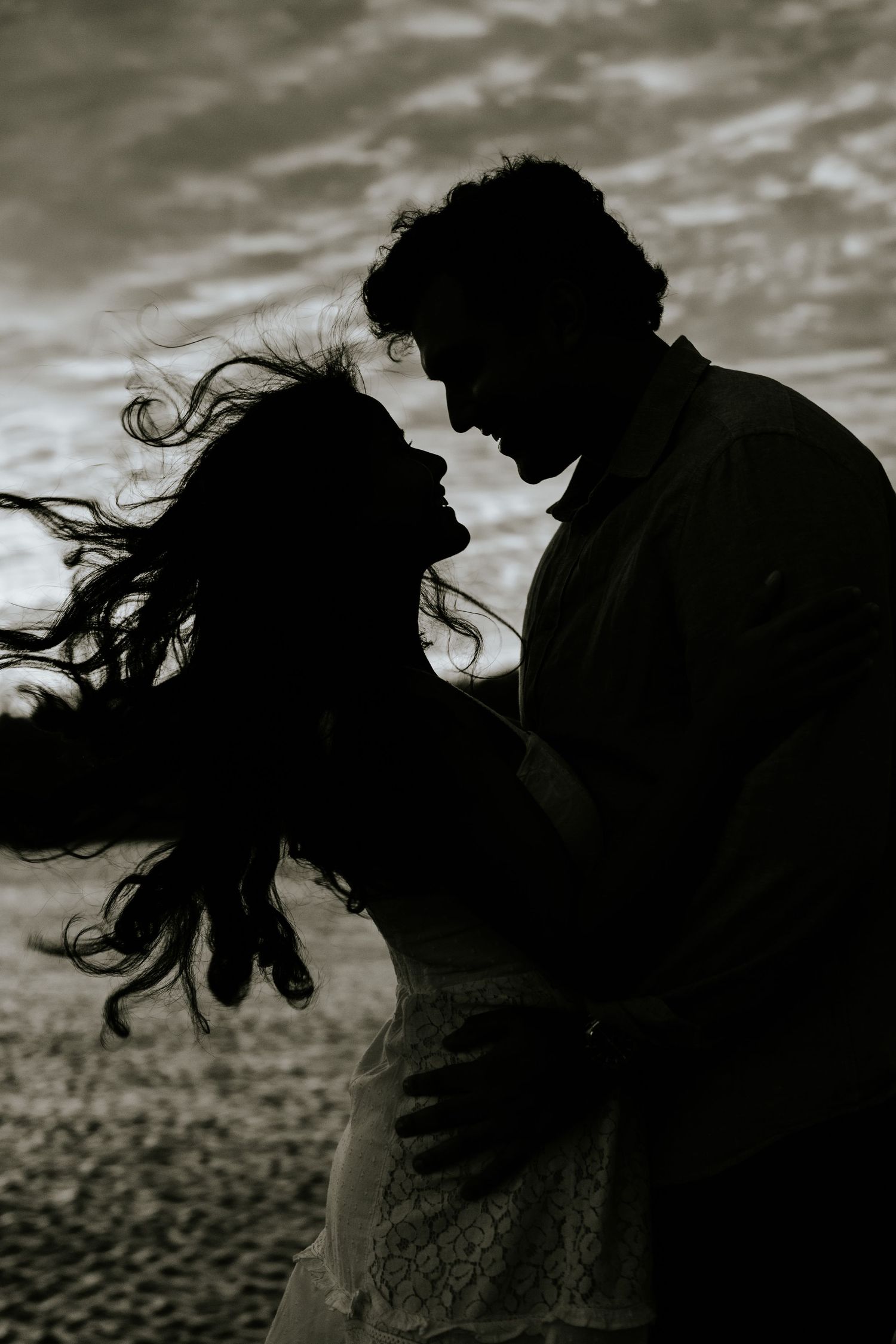 A dramatic black and white photo series shows silhouettes of a couple dancing with flowing hair against a moody sky.