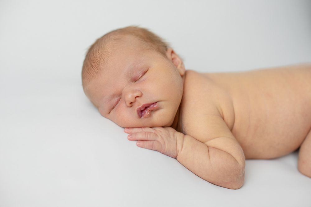 A sleeping newborn baby on a white backdrop
