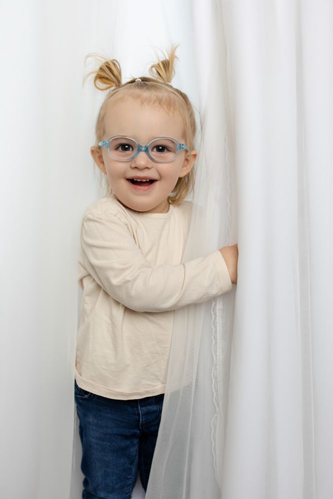 smiling toddler peeking out from curtains
