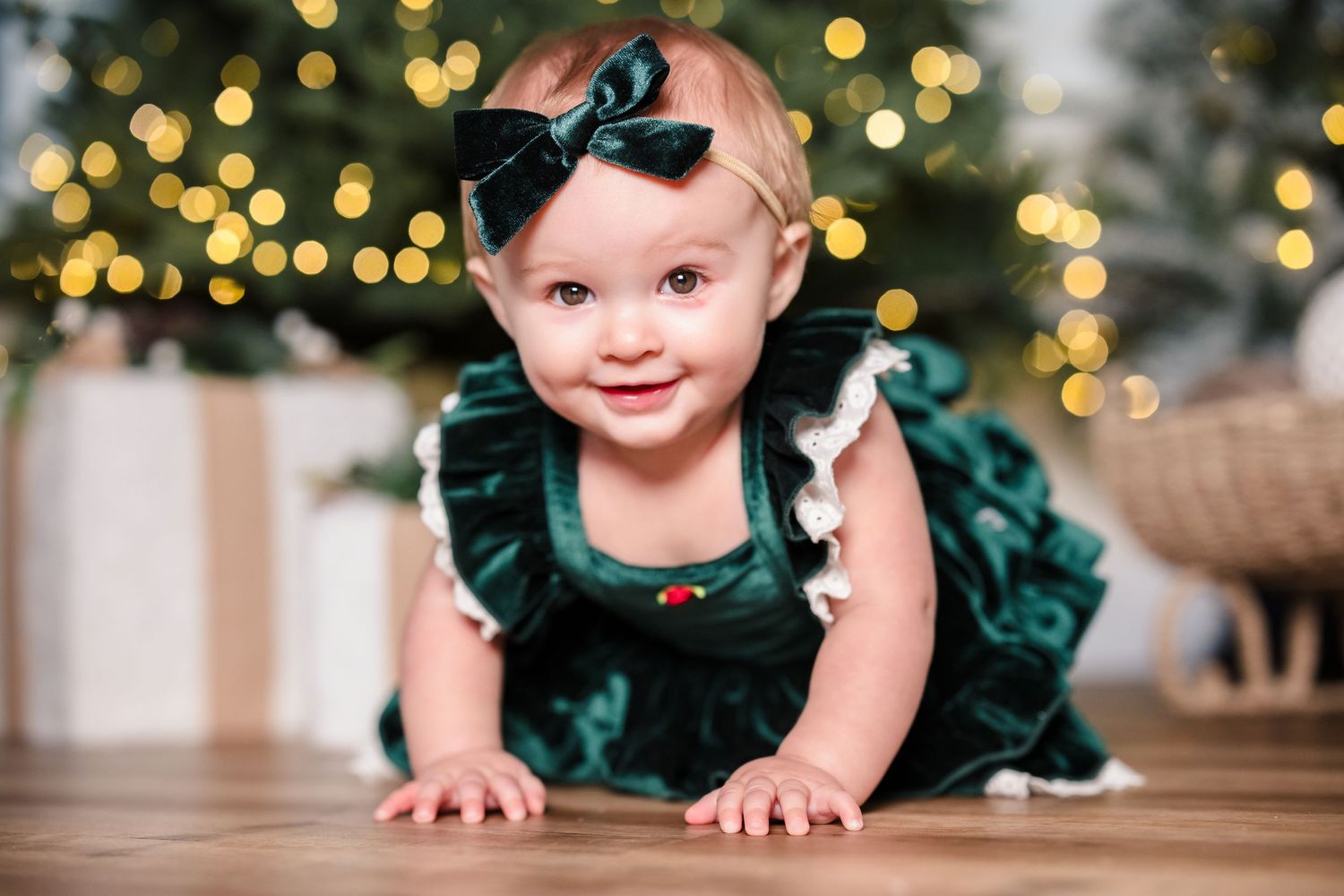 baby crawling in christmas dress in front of tree