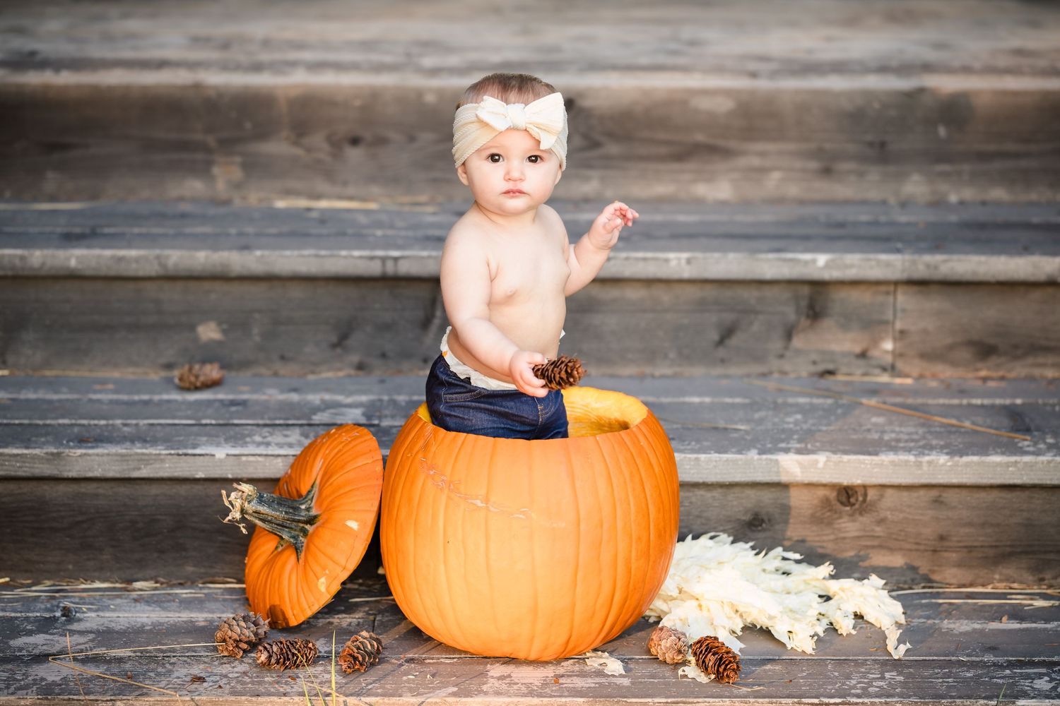baby standing up in pumpkin on stairs