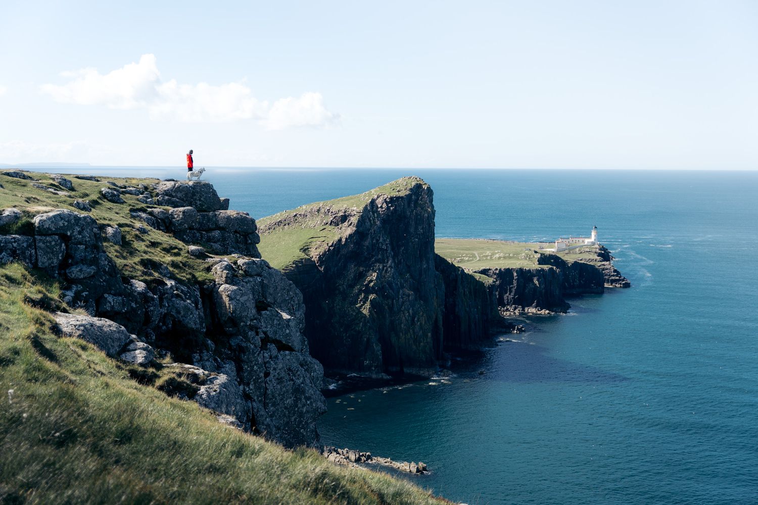 randonneur devant les falaises et le phare de Neist Point sur l'ile de skye en ecosse