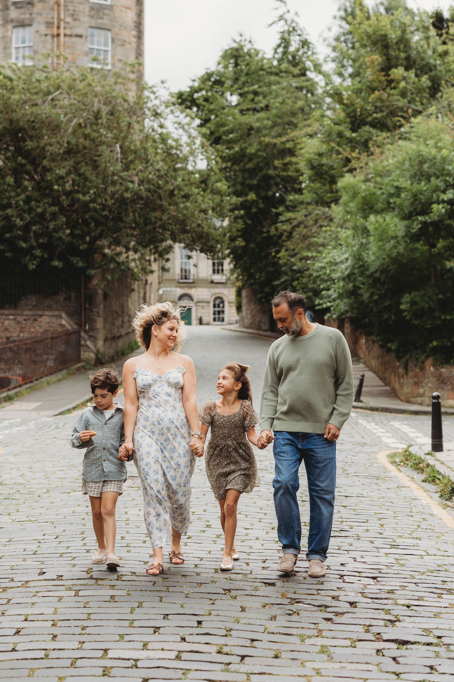 A family walking together on a cobblestone path surrounded by historic buildings.