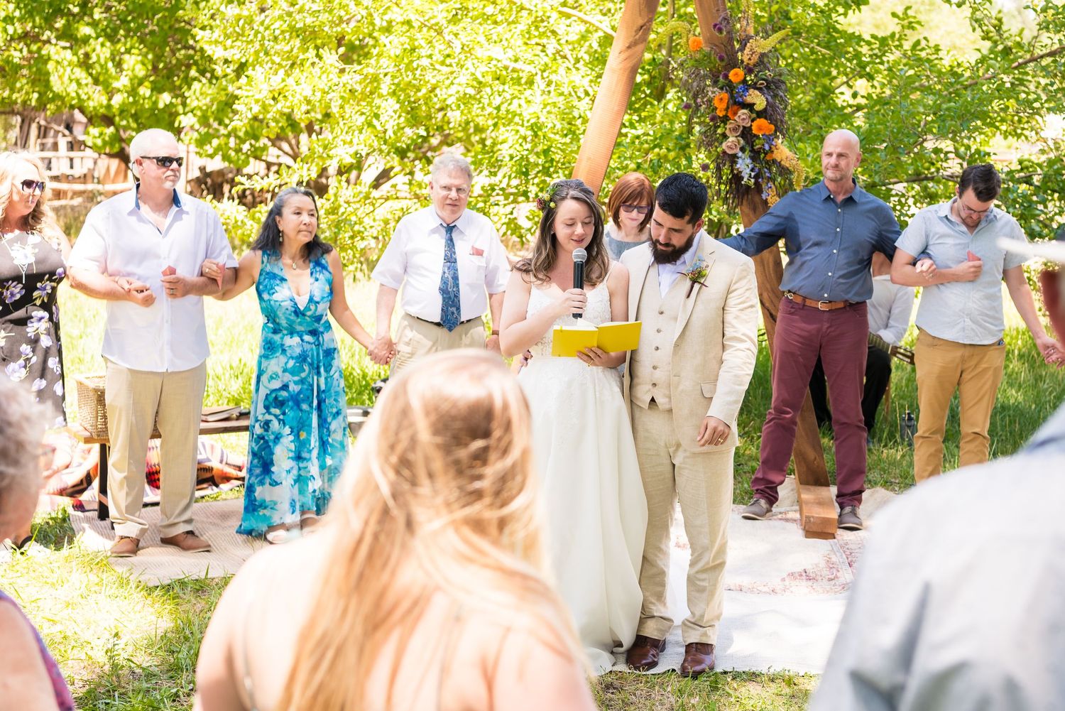 Wedding guests gather outdoors in a garden setting for a summer celebration.
