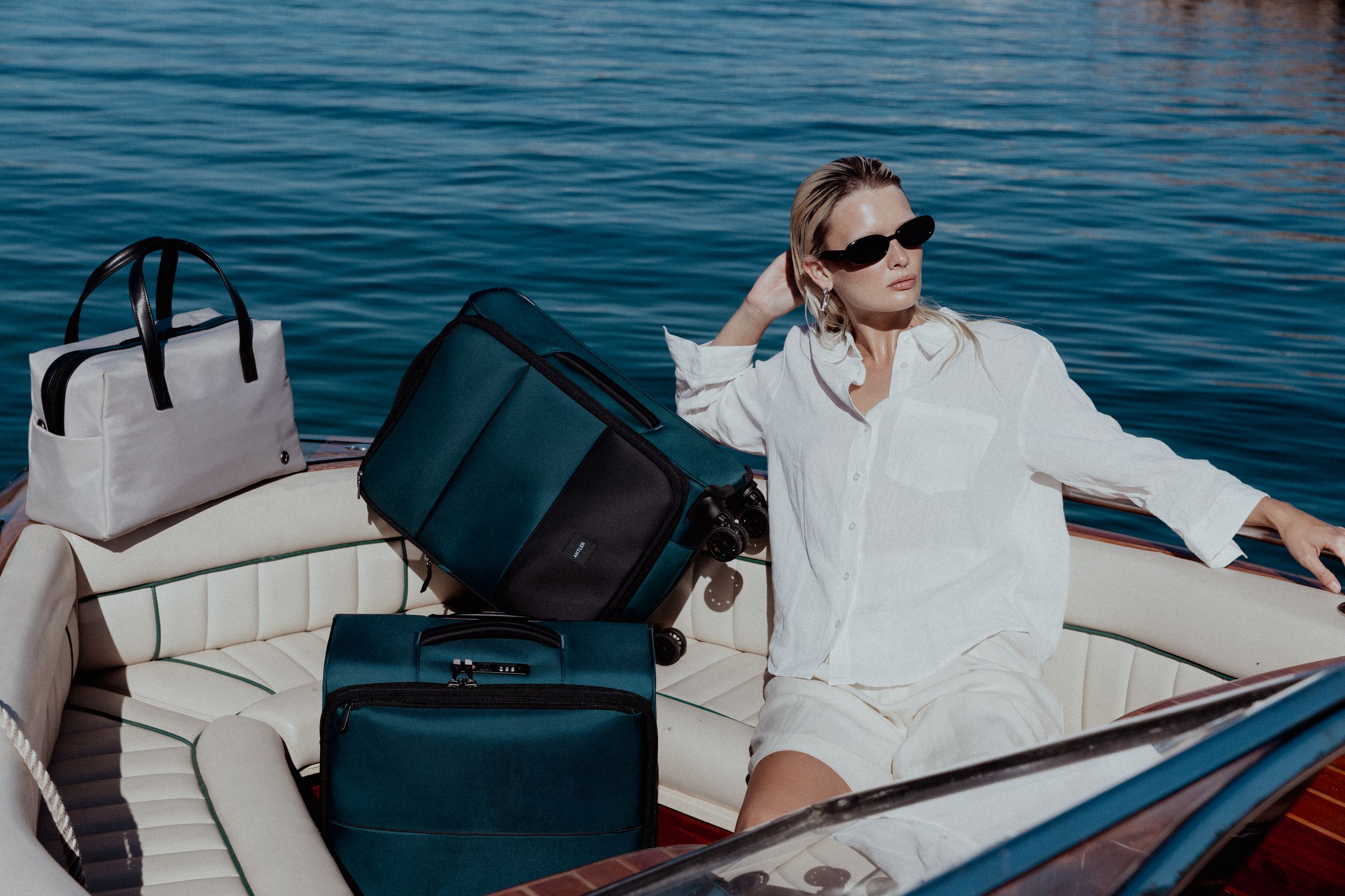 Leisure boating scene with person relaxing among luxury luggage on wooden deck.
