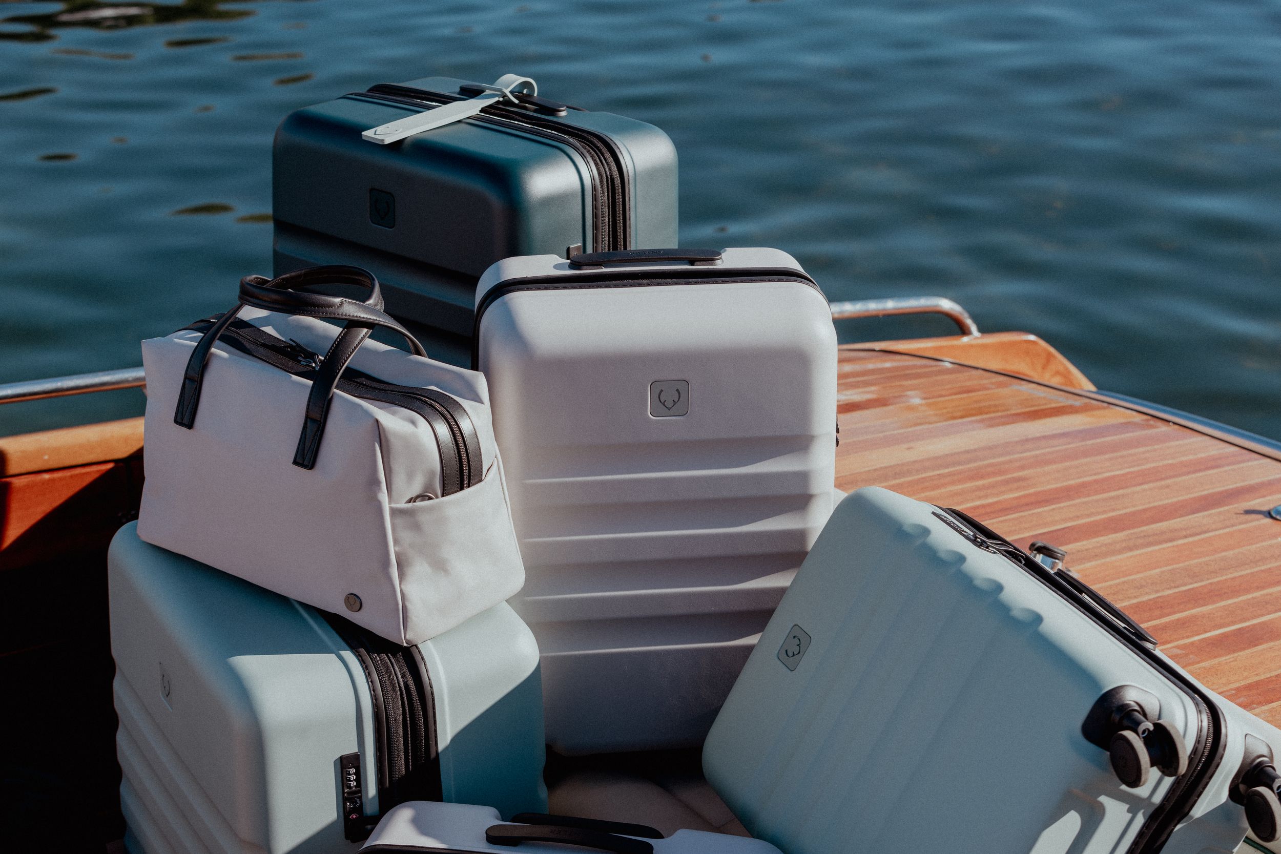 Grey and white luggage cases stacked on wooden boat deck.