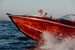 Red speedboat cutting through ocean waves at high speed.