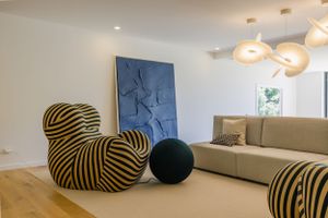 Modern living room with striped accent chairs, blue wall art, and contemporary furnishings.