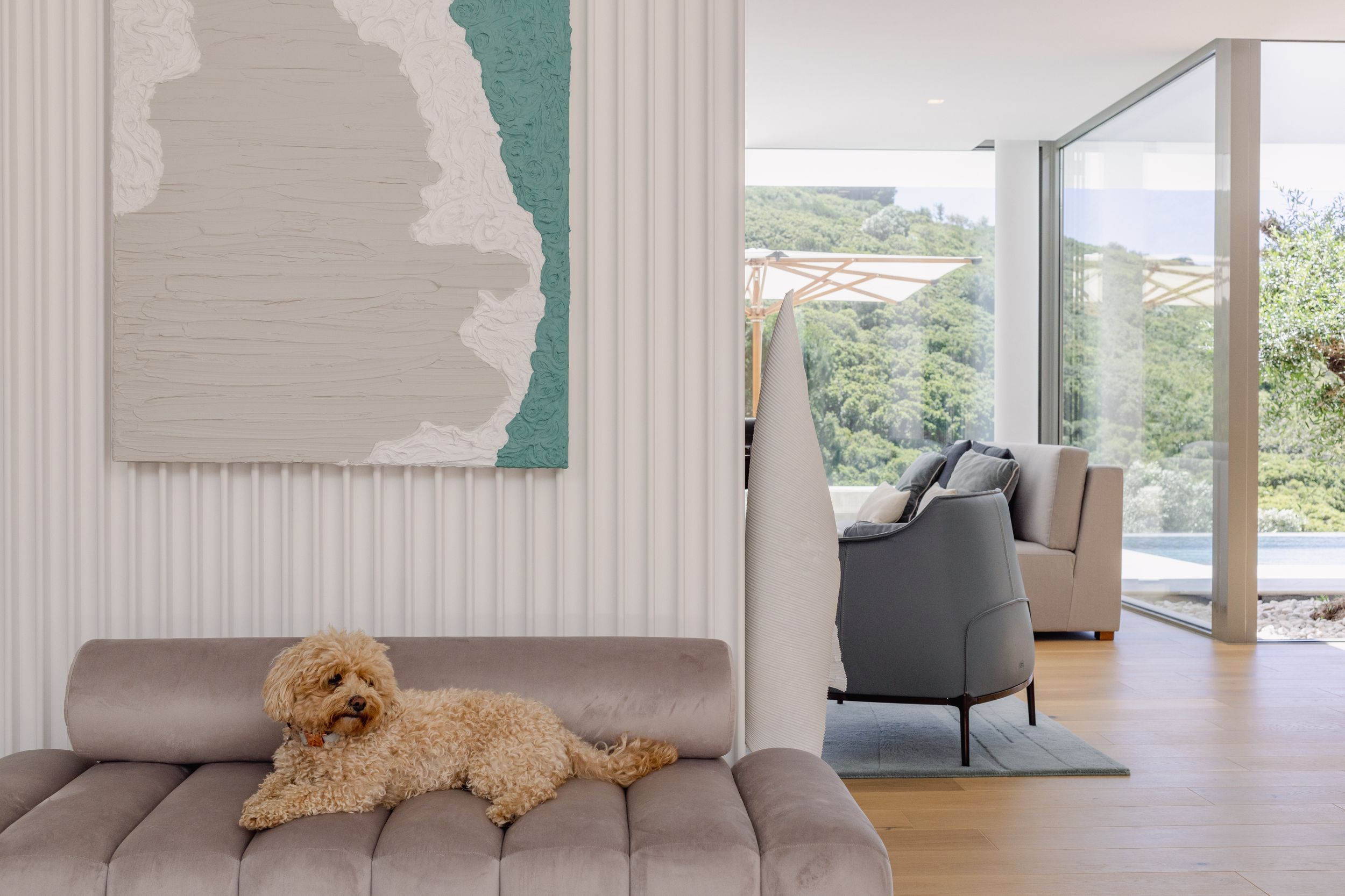 Contemporary living room with abstract wall art and a small dog resting on a gray sofa.