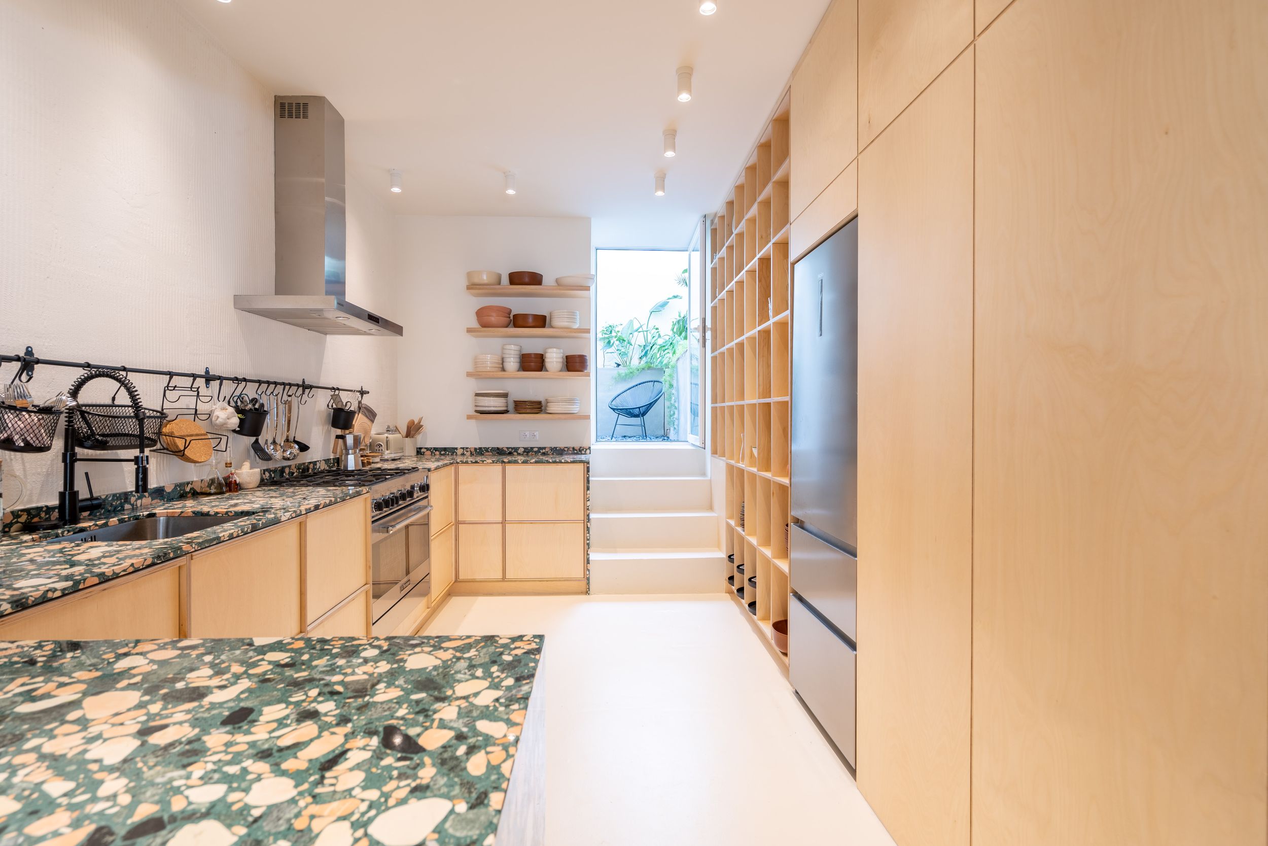 Modern kitchen with light wood cabinets, granite countertops, and stainless steel appliances in a minimalist design.