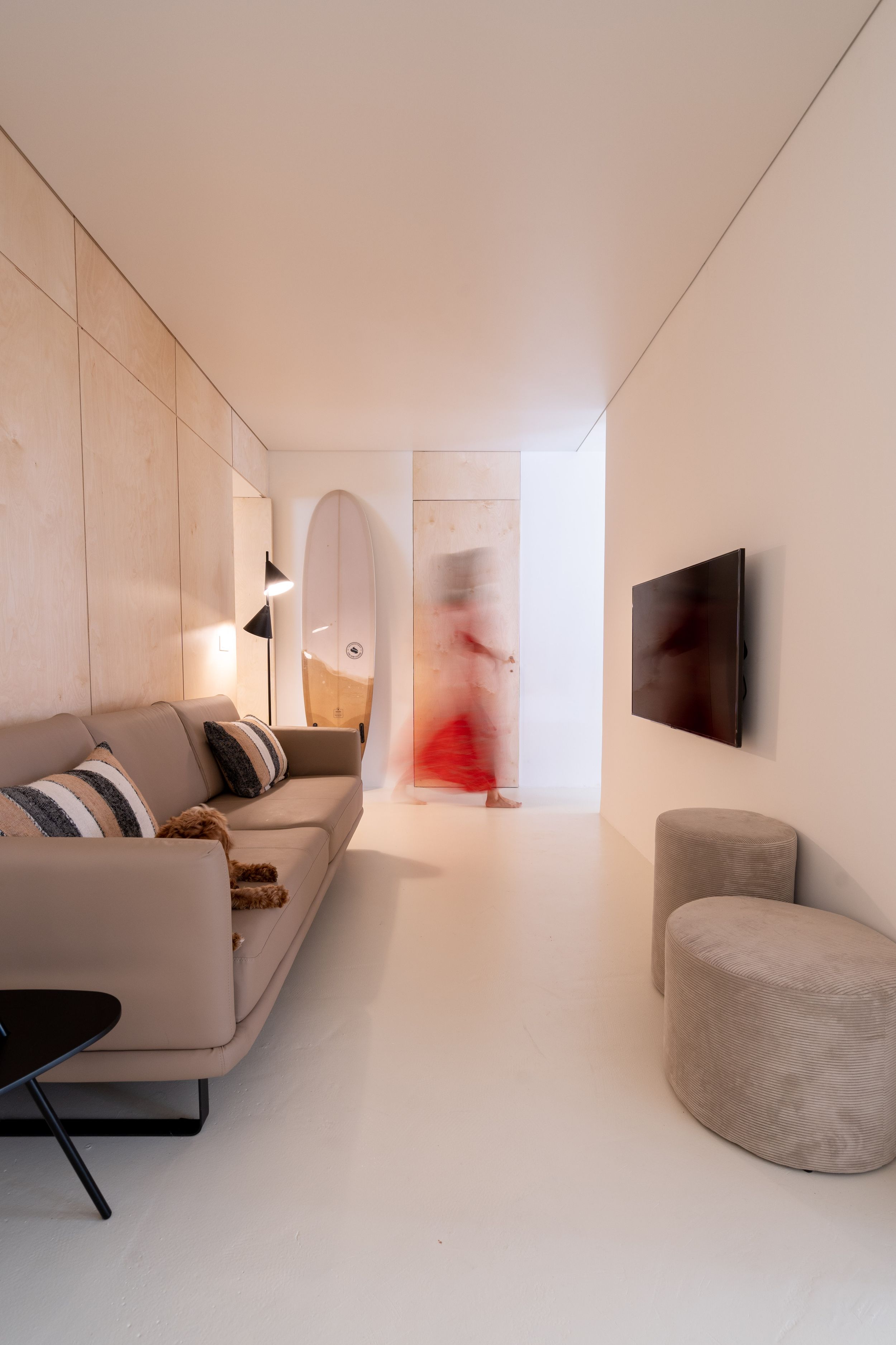 Minimalist living room with white walls, gray sofa, and wall-mounted TV in a contemporary style.