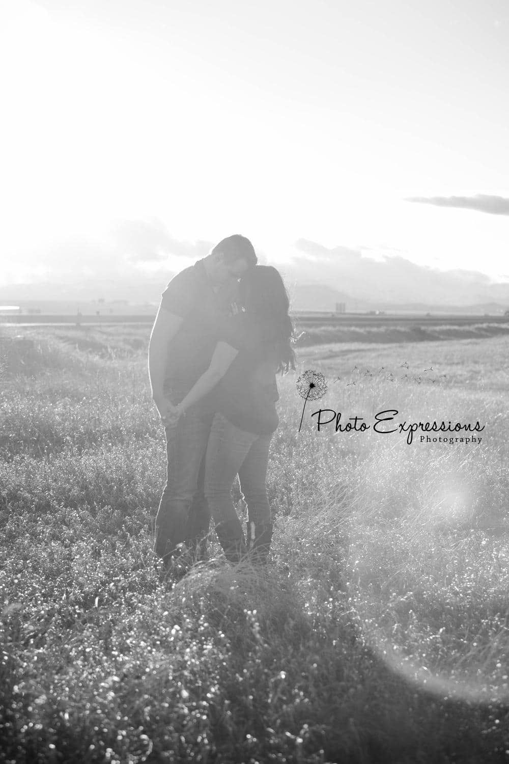 Silhouetted couple embracing in sunlit wildflower meadow.