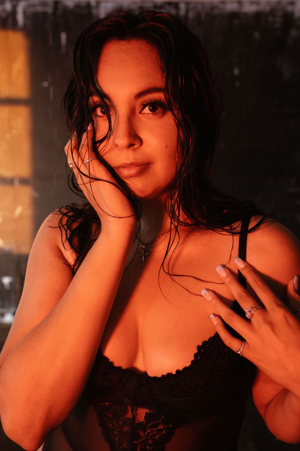 Glamour portrait in warm orange lighting with black lace lingerie and dramatic styling.