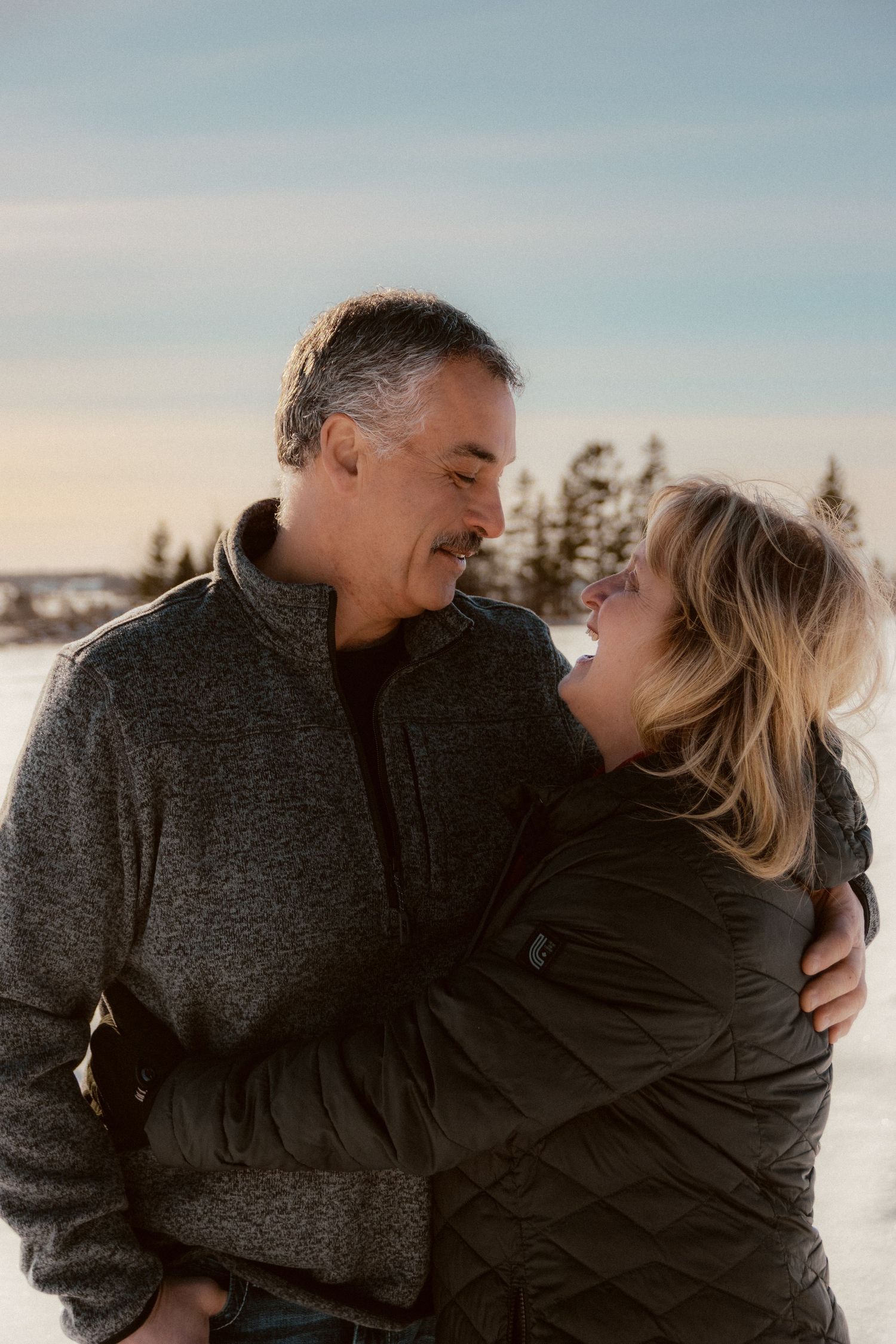 Intimate winter portrait of a couple embracing outdoors in snowy weather.