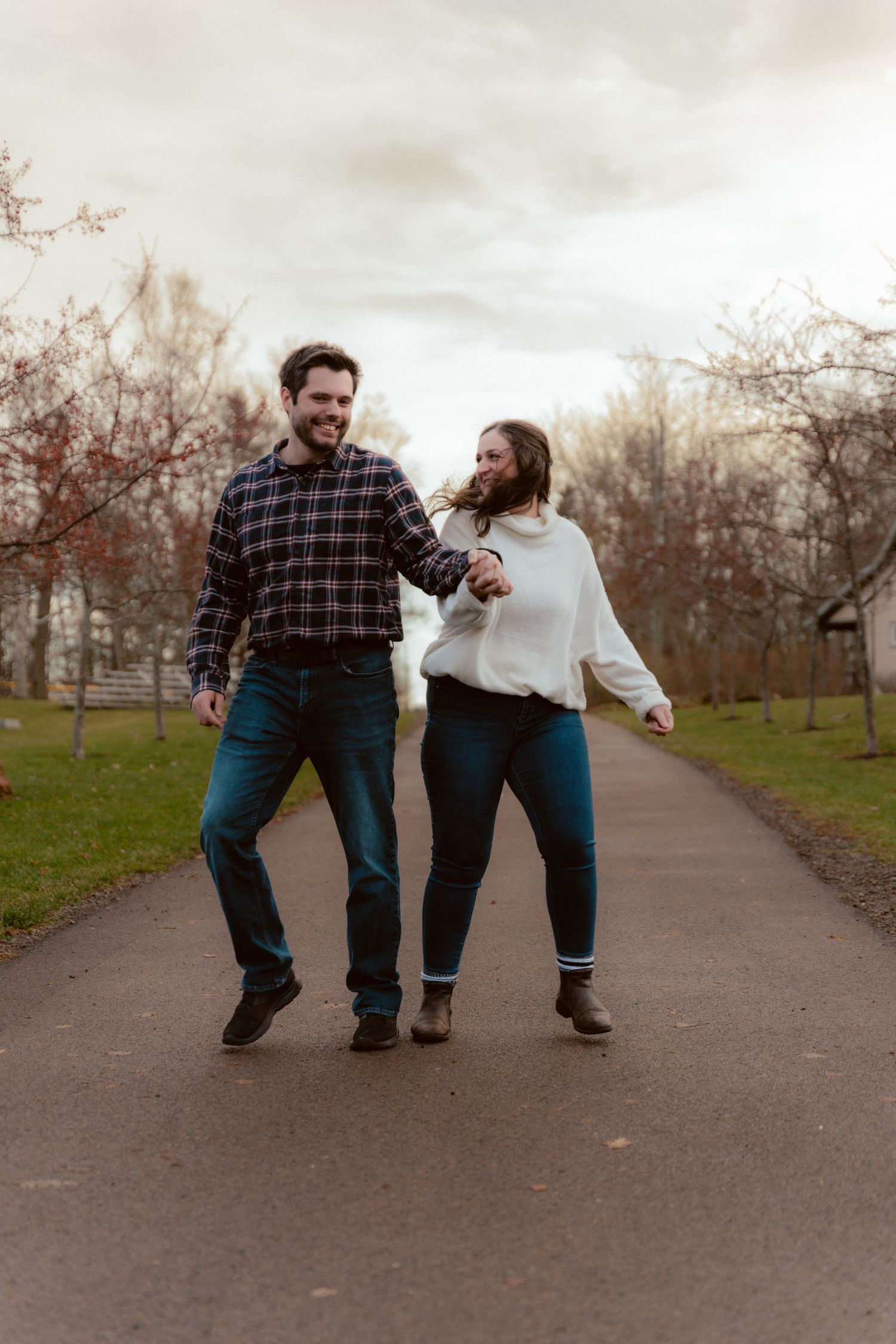 A joyful couple walking together on a path during a cloudy autumn day.