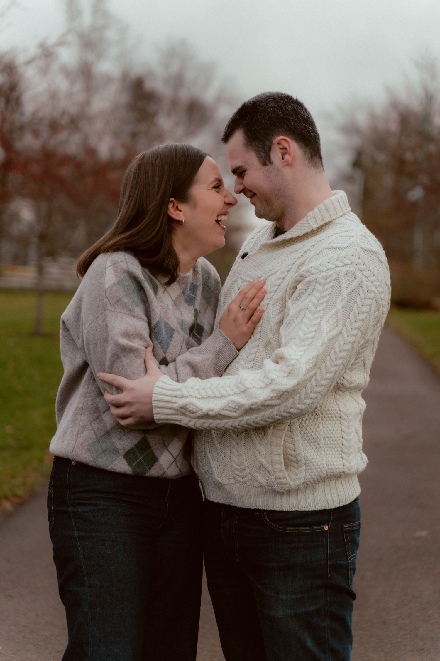 A romantic couple sharing a tender moment on a path during autumn, wearing cozy sweaters against the cool weather.