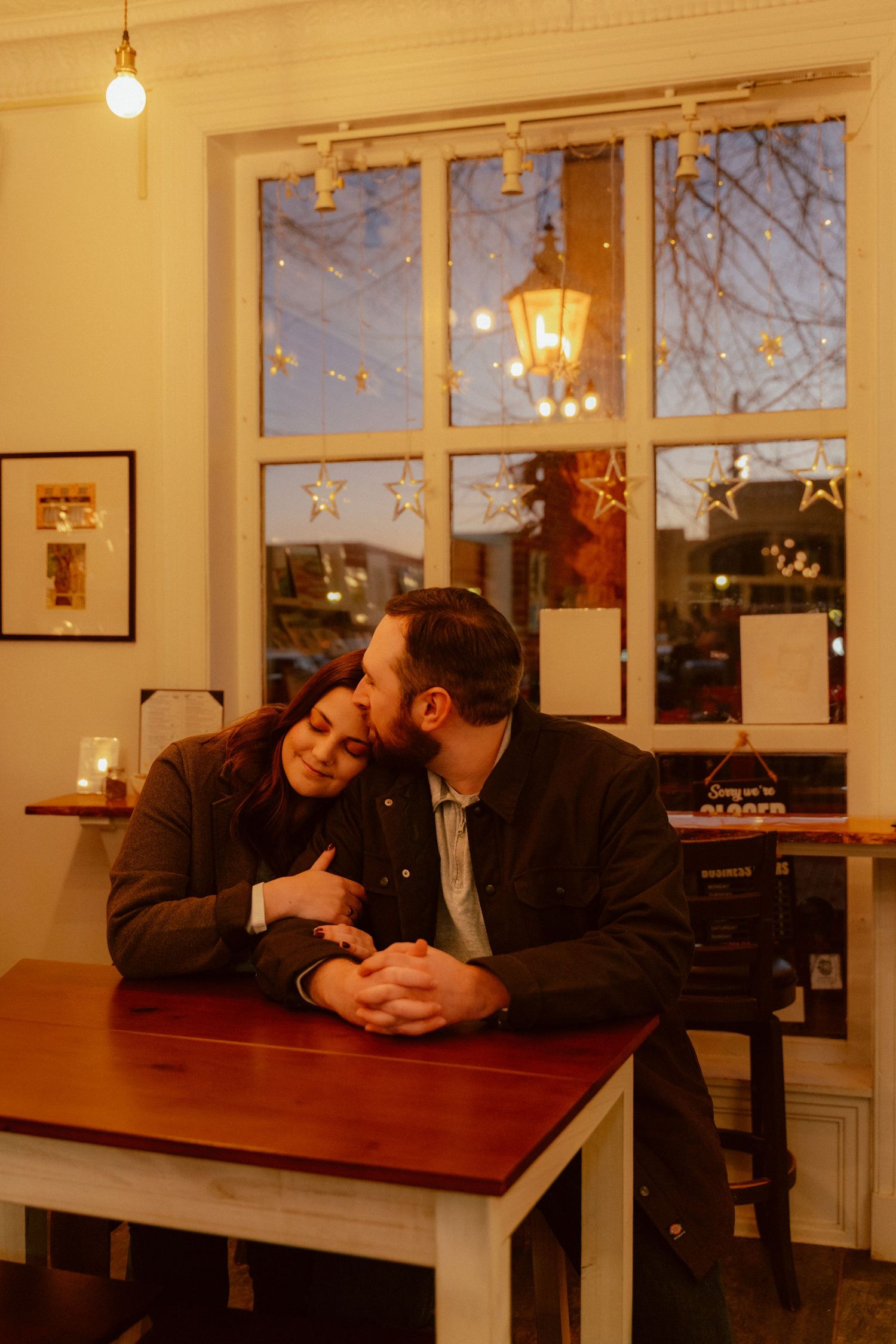 A couple shares an intimate moment at a cozy restaurant table near a window during golden hour.