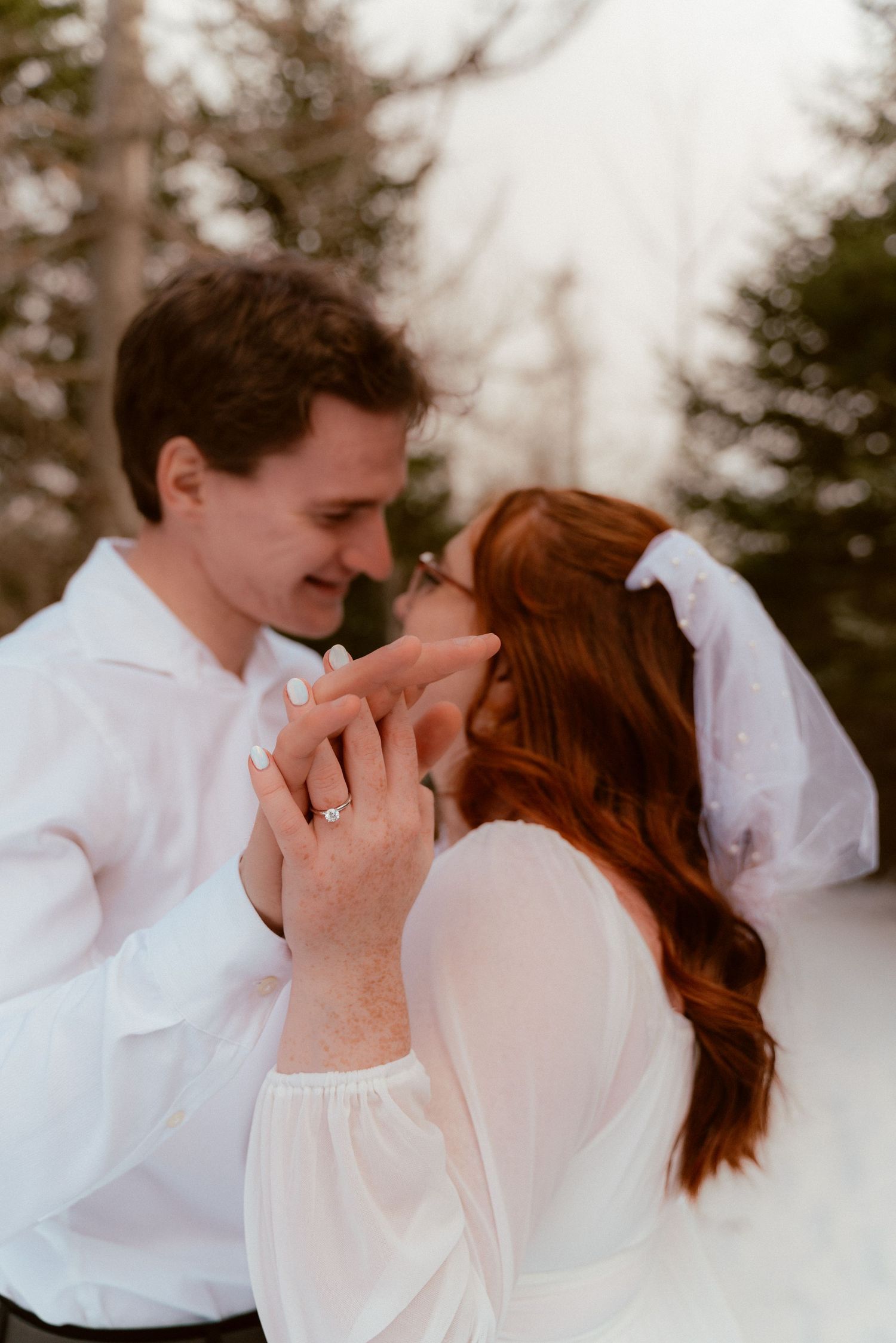 An intimate wedding portrait capturing a tender moment between newlyweds against a snowy winter backdrop.