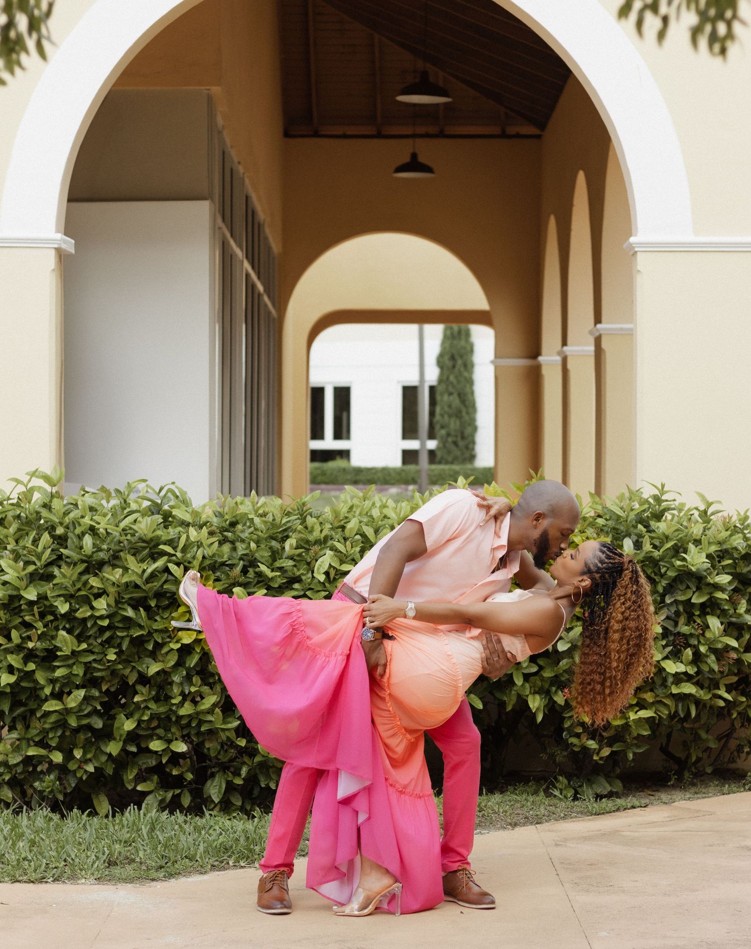 A romantic dip pose under an arched walkway with Mediterranean architecture.