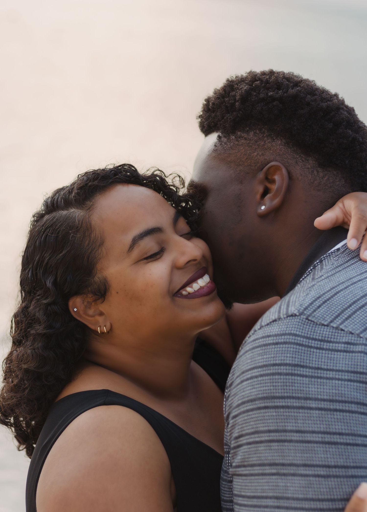 A romantic beach portrait capturing a joyful couple in an intimate moment during sunset.