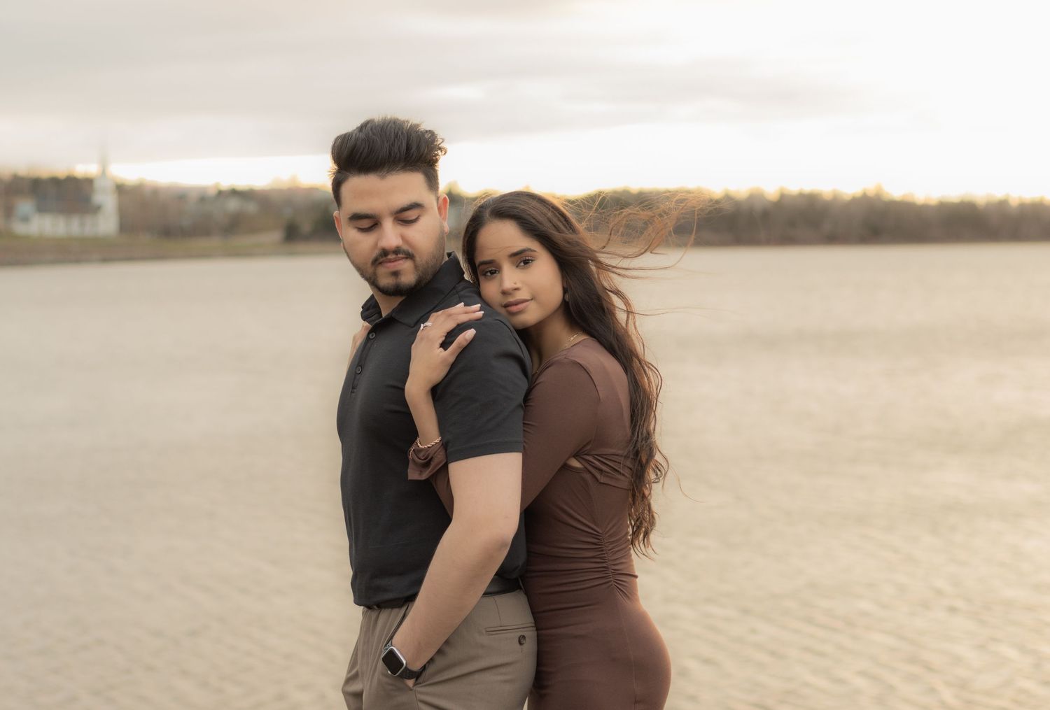 Stylish couple poses together on an open beach landscape.