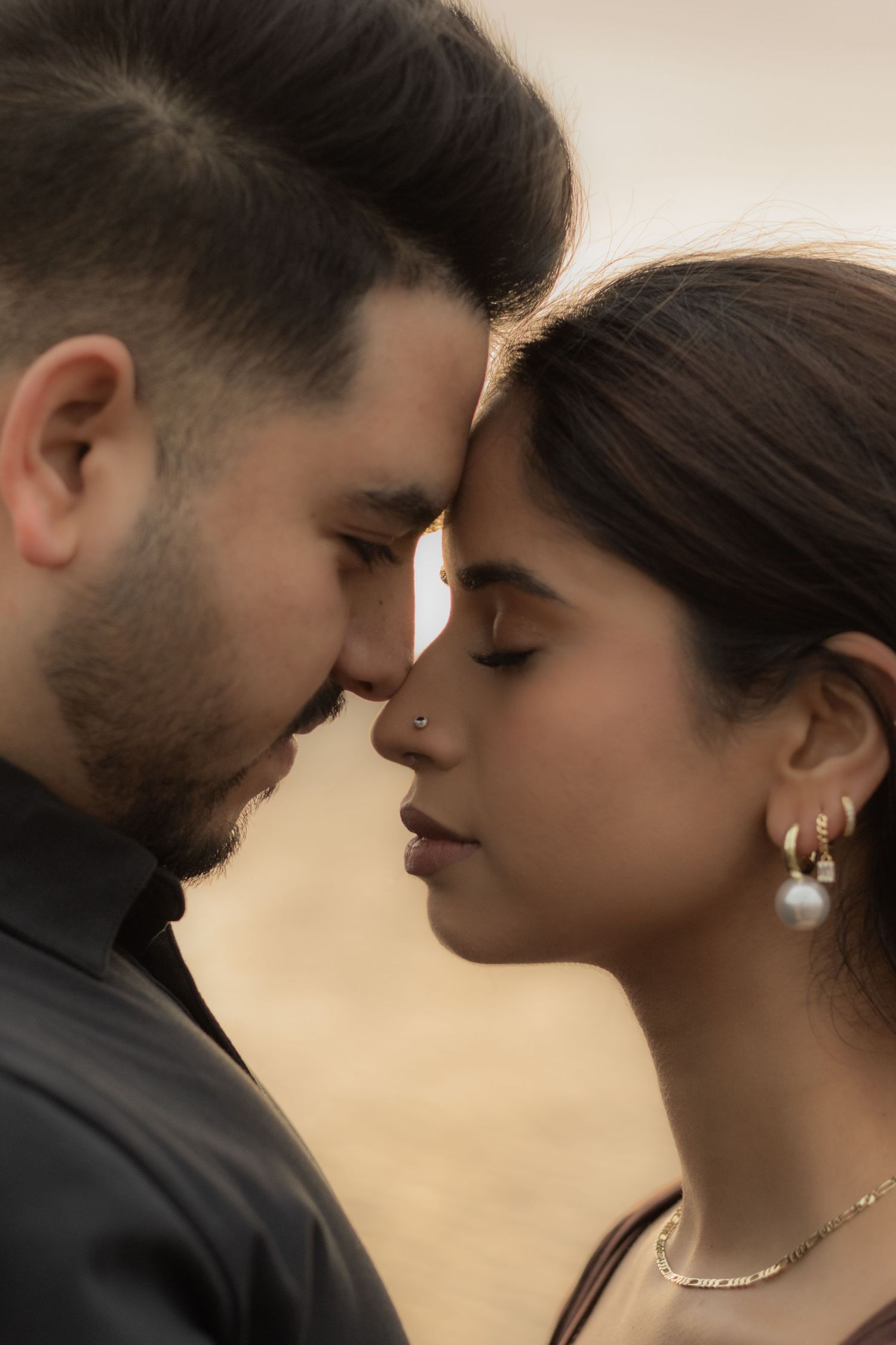 Intimate close-up portrait of couple sharing tender moment at sunset.