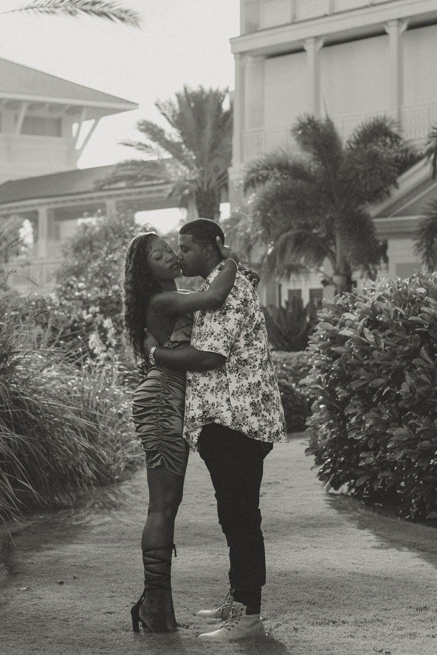 A romantic black and white portrait of a couple sharing an intimate moment outdoors.