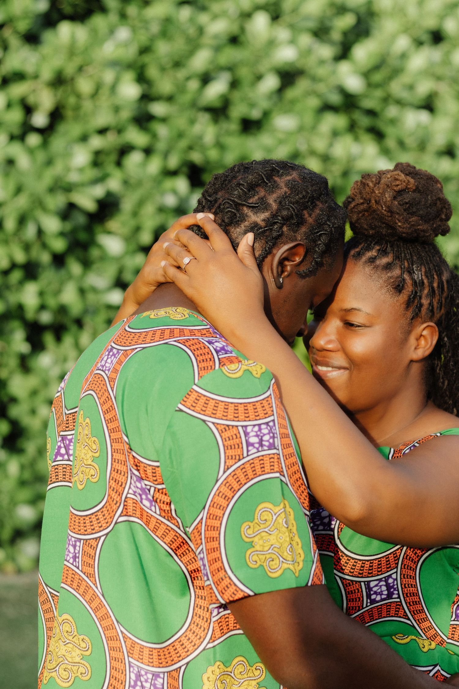 Intimate moment captured between couple in matching green African print attire.