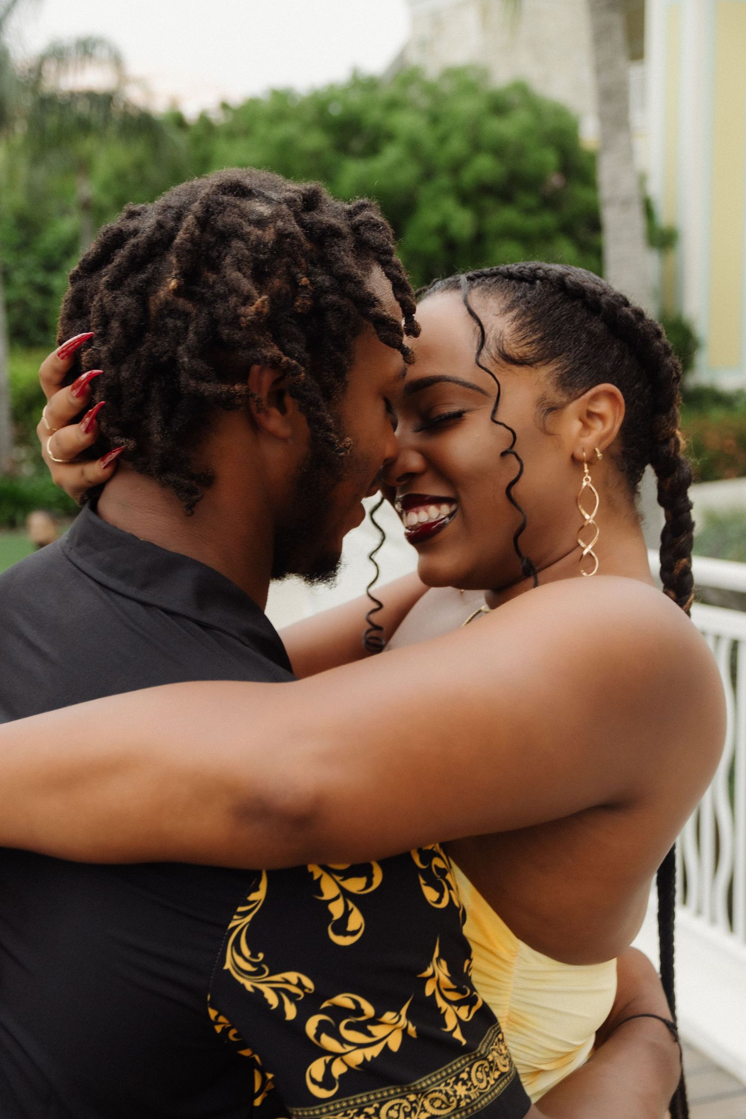 A joyful couple sharing a tender moment in a tropical garden setting.
