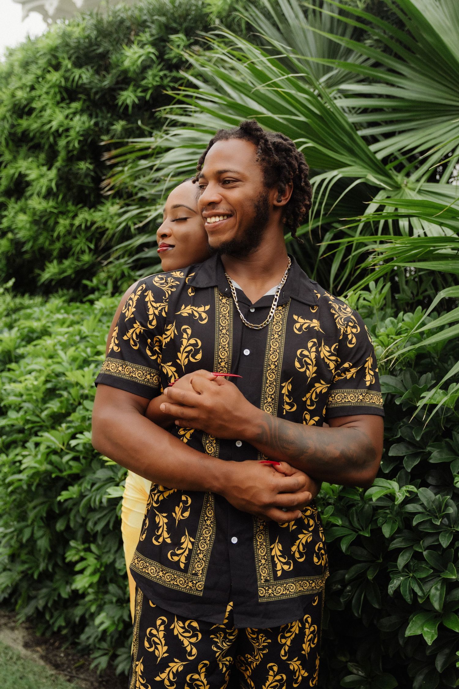A happy couple sharing a tender moment against tropical palm foliage.