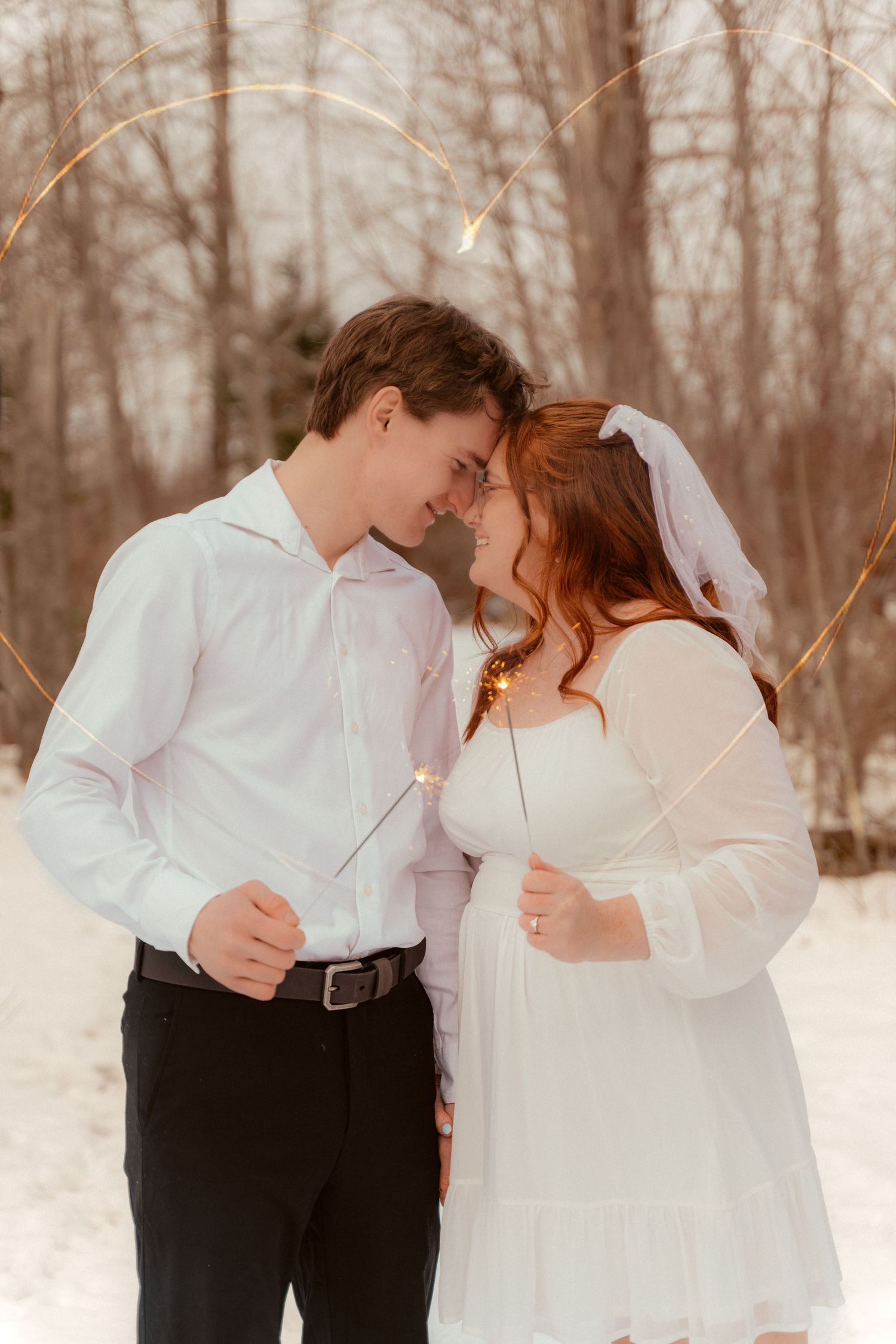 A romantic winter wedding photo of a couple sharing an intimate moment in a snowy forest setting.