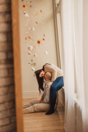 An image in a mirror of a couple with flowers floating through sunlit room.