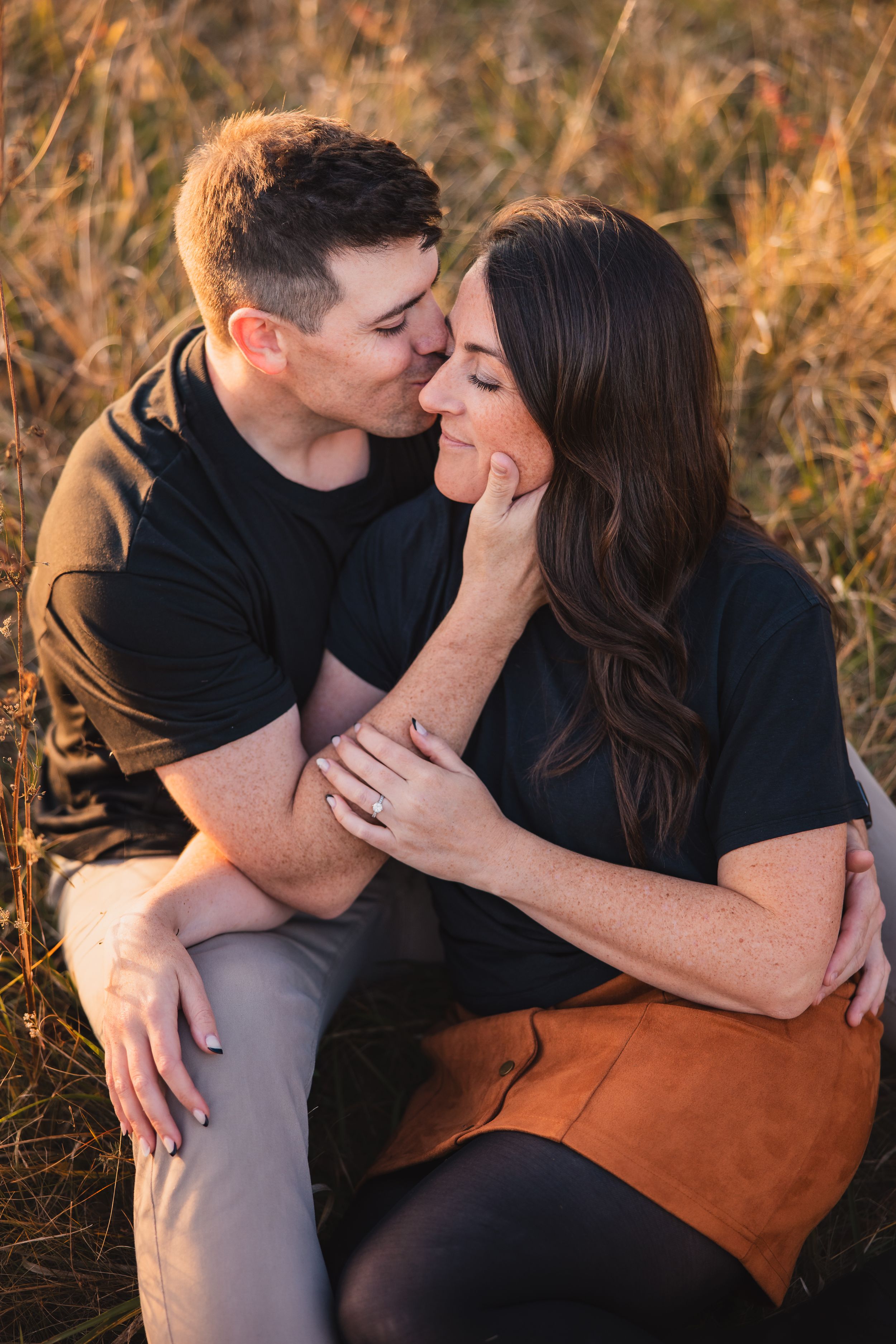 A tender romantic moment captured between a couple in golden autumn field at sunset.