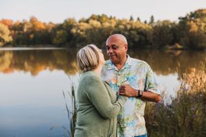 A couple sits together on a wooden dock at sunset, enjoying a romantic moment by a tranquil lake.