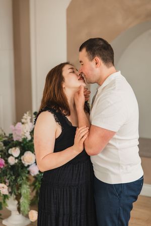 A romantic couple shares intimate moments in a series of four photos against a light backdrop with floral decorations.