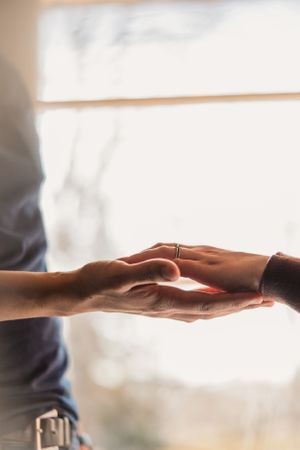 Two hands reaching toward each other against a bright white background in a gesture of connection and support.