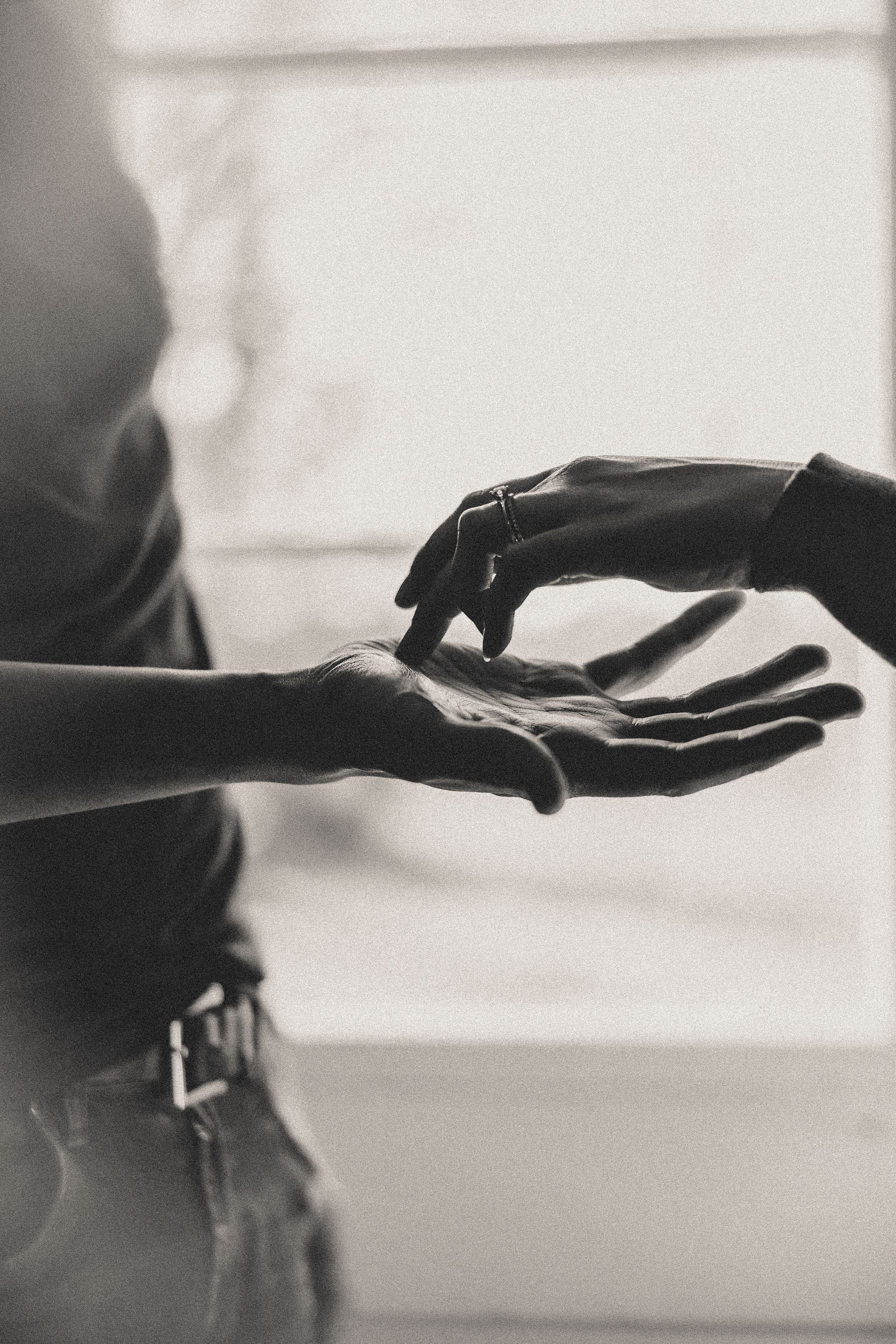 Black and white artistic photograph series showing hands reaching toward each other in silhouette against a light background.