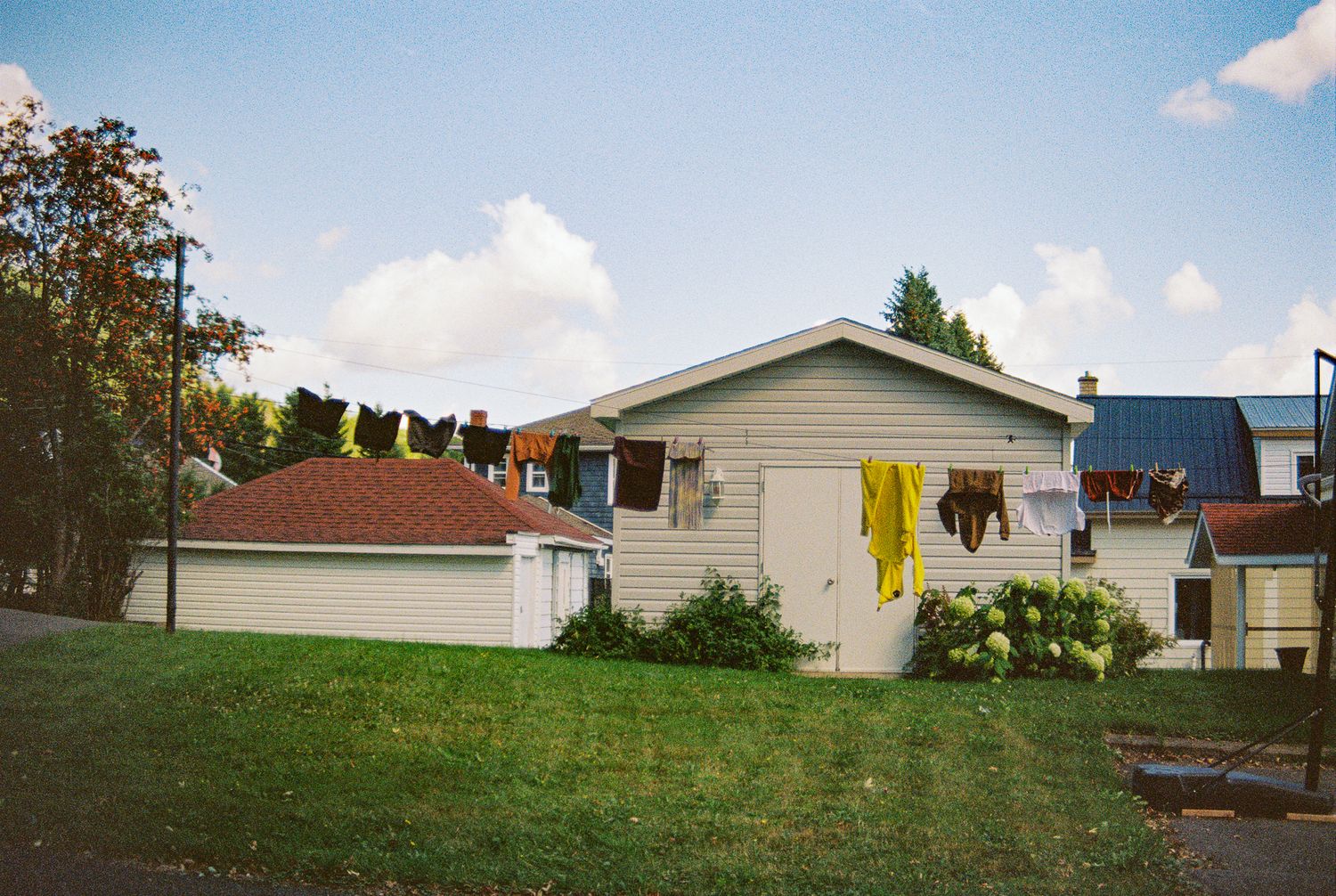 Suburban house with laundry hanging on clothesline in backyard.