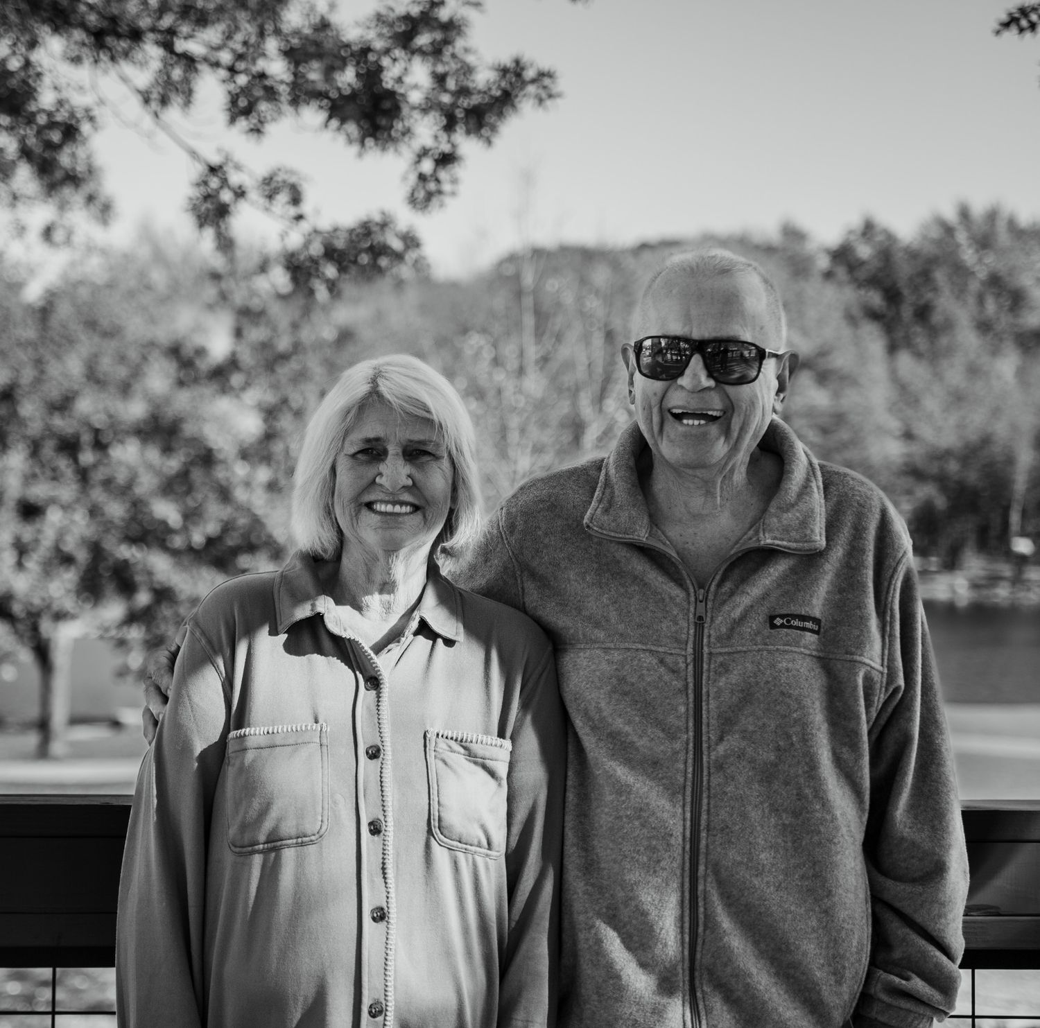 Two elderly people share a joyful moment together outdoors in black and white.