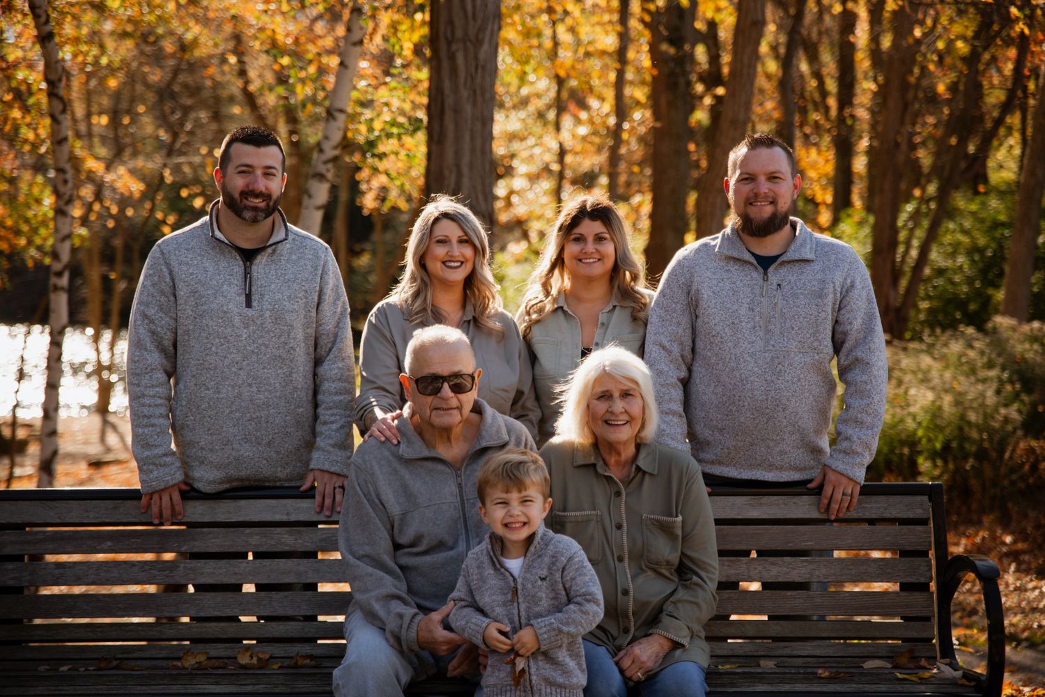 Family members sitting together on a wooden bench during golden autumn hour.