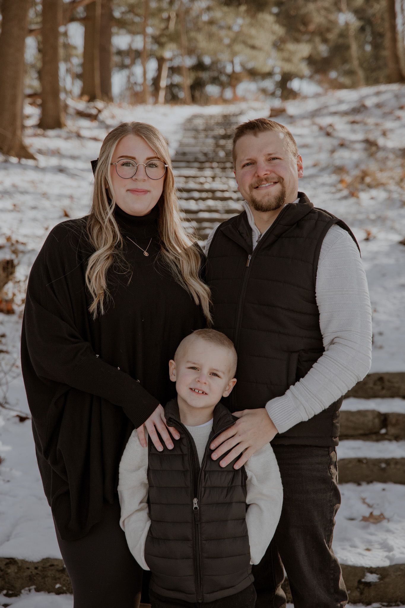 Winter family photos in snowy forest setting wearing coordinated black and white outfits.