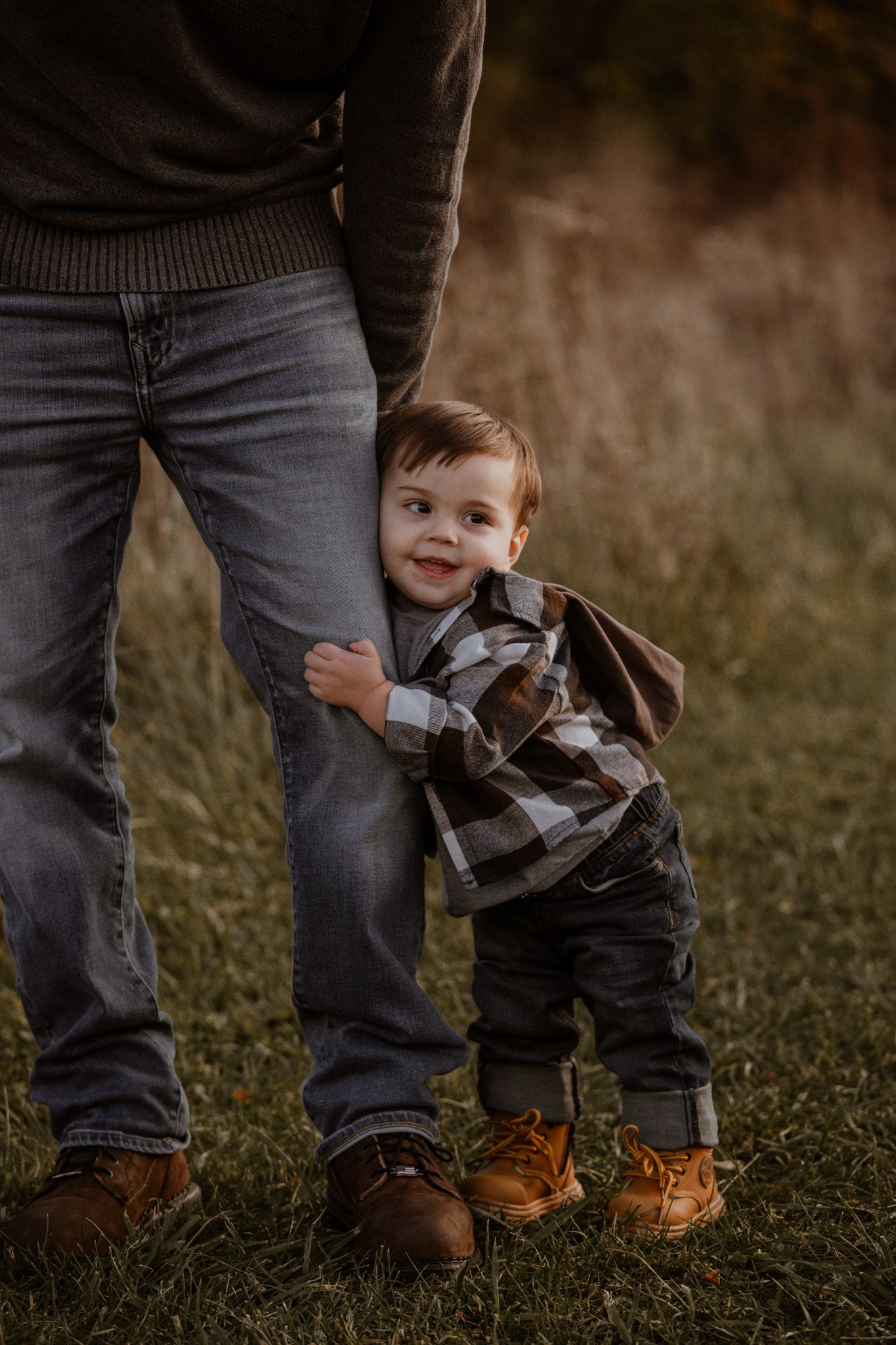 Playful shots focusing on feet and legs of a small child in plaid shirt playing with adults outdoors.